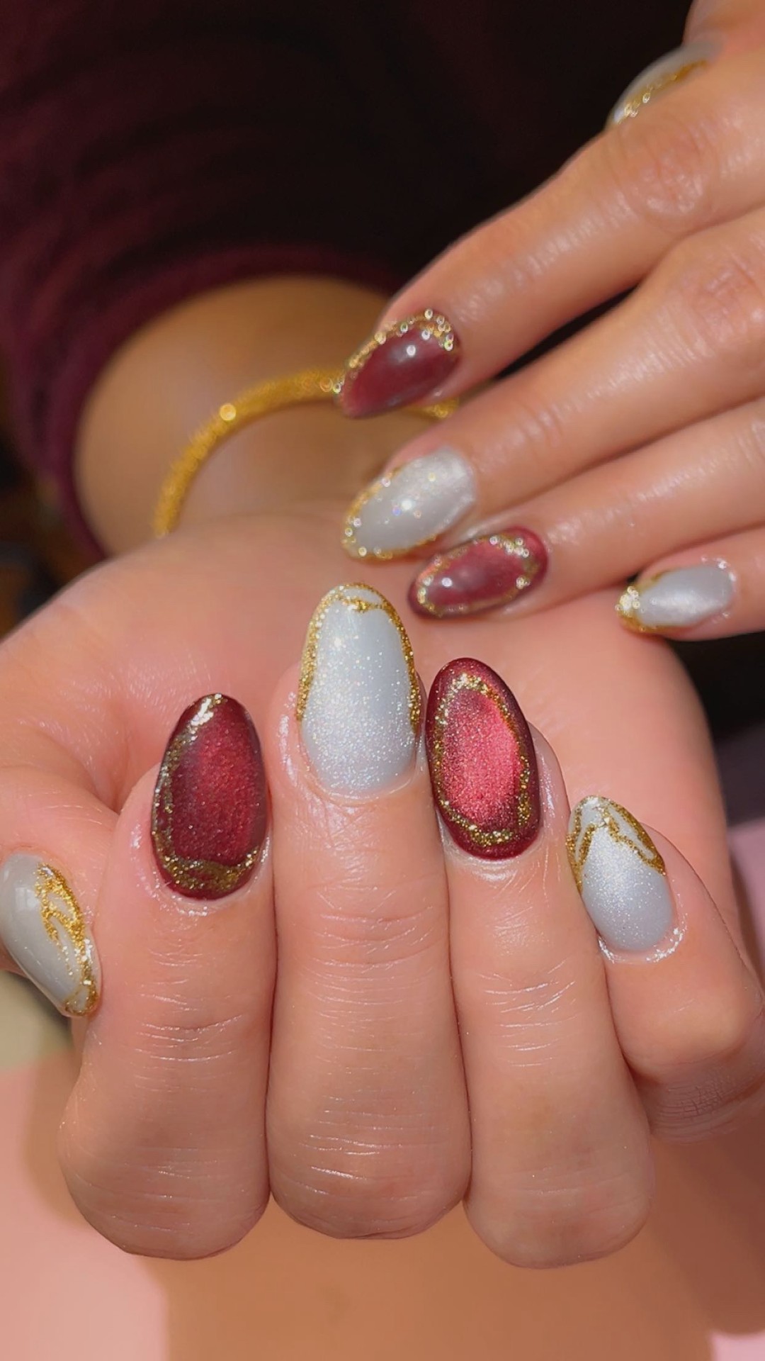Burgundy and pearl cat-eye gel nails with gold detailing